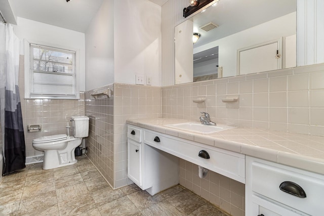 full bathroom featuring visible vents, toilet, a wainscoted wall, vanity, and tile walls