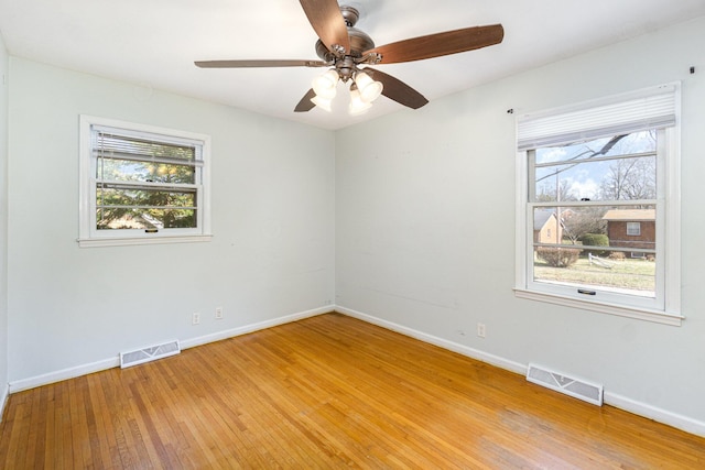 unfurnished room featuring light wood-style floors, visible vents, and a wealth of natural light