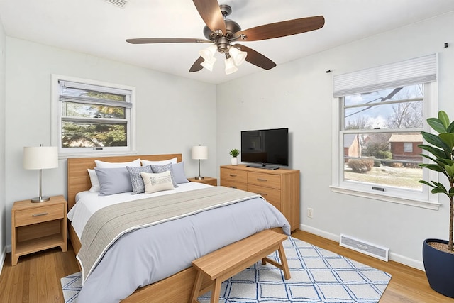 bedroom featuring ceiling fan, light wood-type flooring, visible vents, and baseboards