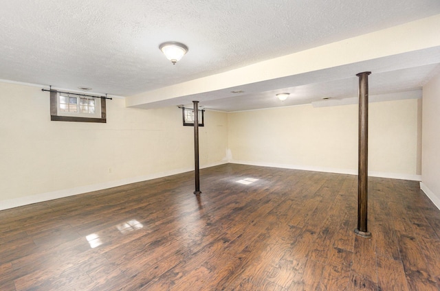 basement featuring a textured ceiling, baseboards, and wood finished floors