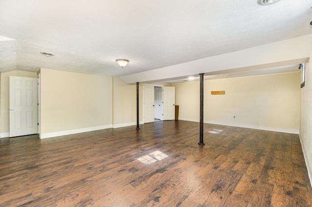 finished basement featuring a textured ceiling, baseboards, and wood finished floors