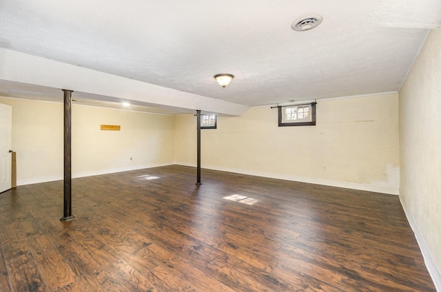 below grade area featuring a textured ceiling, wood finished floors, visible vents, and baseboards