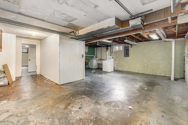 below grade area featuring washer / dryer, electric panel, and concrete block wall