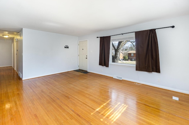 empty room with light wood-style floors, baseboards, and visible vents