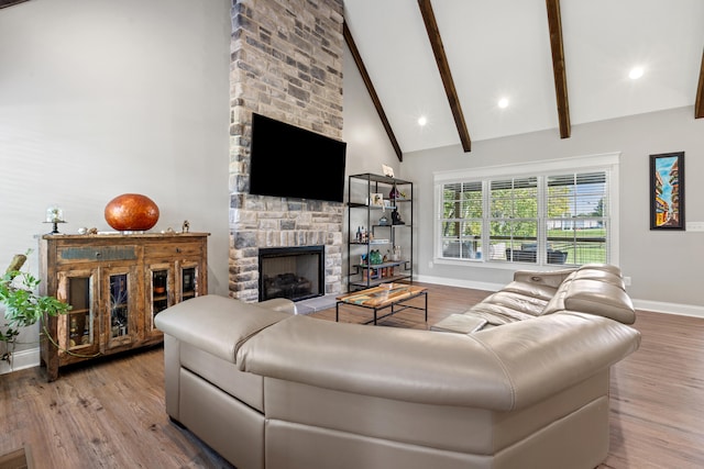 living area featuring high vaulted ceiling, a fireplace, beamed ceiling, and wood finished floors