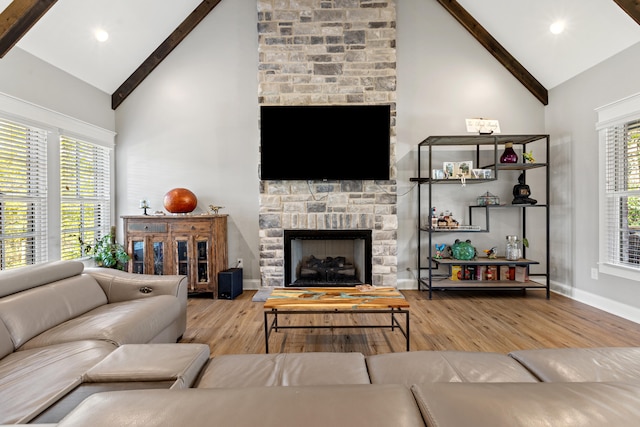 living area featuring beam ceiling, a fireplace, high vaulted ceiling, and wood finished floors