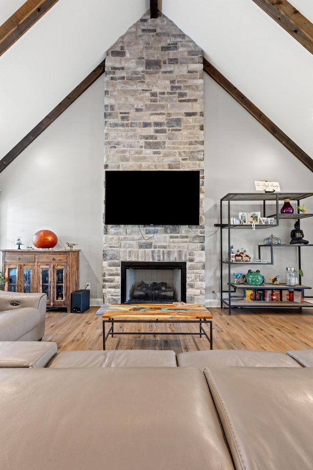 living area featuring beam ceiling, a fireplace, wood finished floors, high vaulted ceiling, and baseboards