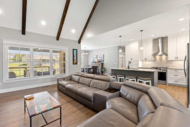 living room featuring light wood finished floors, recessed lighting, beam ceiling, and baseboards