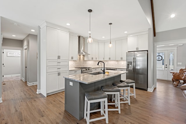 kitchen with light wood-style flooring, white cabinetry, appliances with stainless steel finishes, decorative backsplash, and wall chimney exhaust hood