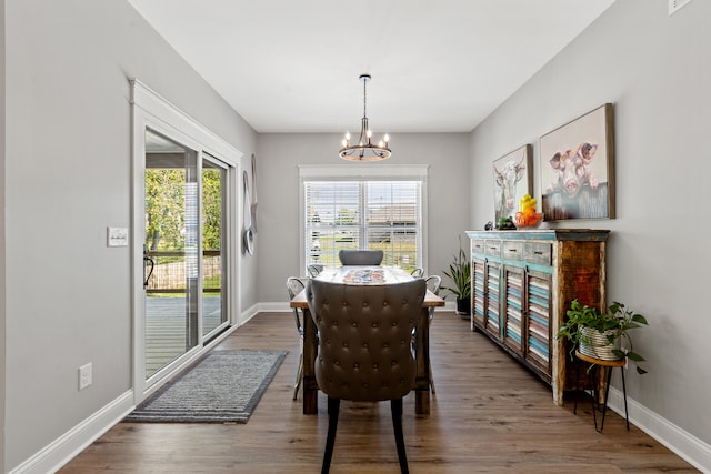 dining area with baseboards, wood finished floors, and an inviting chandelier