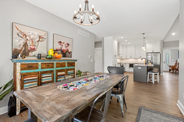 dining area with light wood-style floors, baseboards, visible vents, and a chandelier