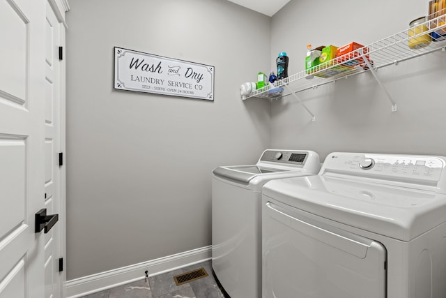 clothes washing area featuring laundry area, visible vents, washer and clothes dryer, and baseboards