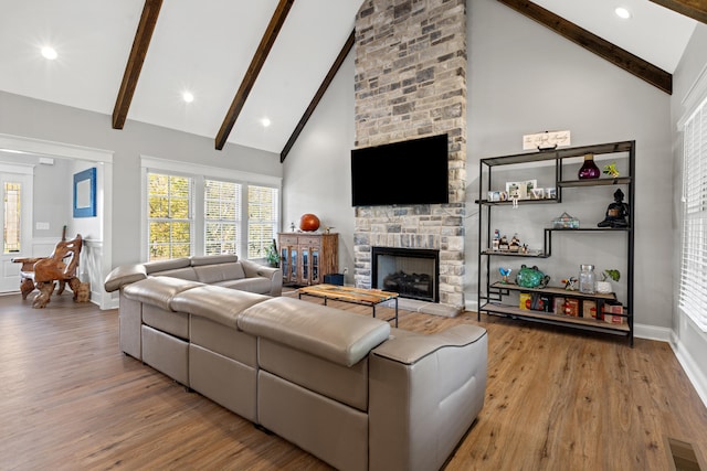 living room with high vaulted ceiling, visible vents, a stone fireplace, and wood finished floors