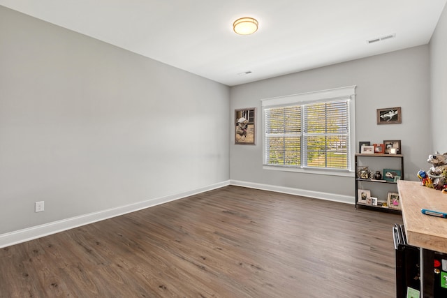 unfurnished room with visible vents, dark wood finished floors, and baseboards