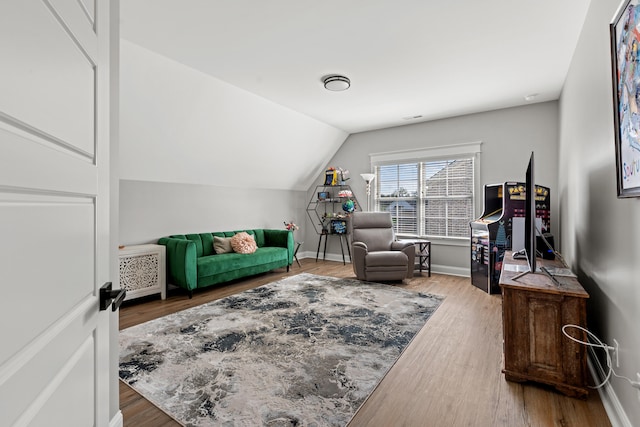 living area with visible vents, vaulted ceiling, baseboards, and wood finished floors