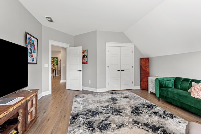 living room featuring lofted ceiling, wood finished floors, visible vents, and baseboards