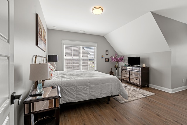 bedroom with lofted ceiling, wood finished floors, visible vents, and baseboards