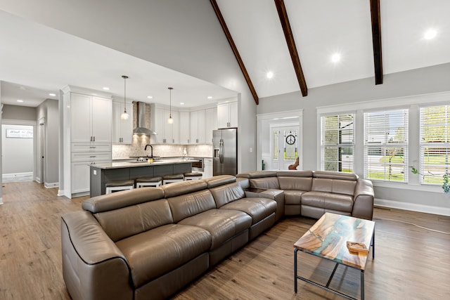 living room with beam ceiling, recessed lighting, light wood-style floors, high vaulted ceiling, and baseboards