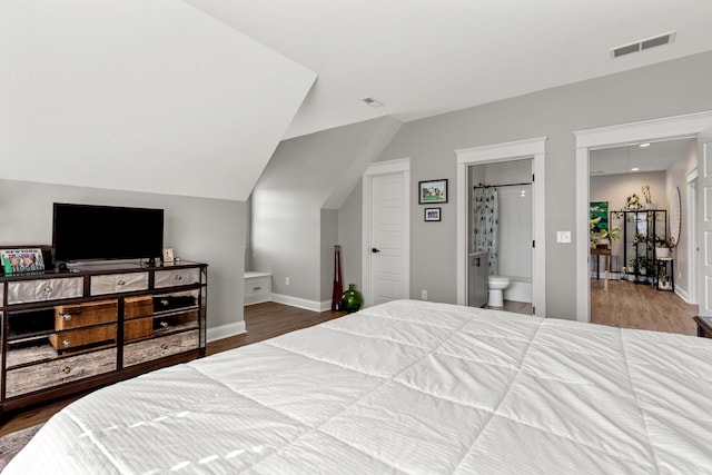 bedroom featuring baseboards, visible vents, vaulted ceiling, and wood finished floors