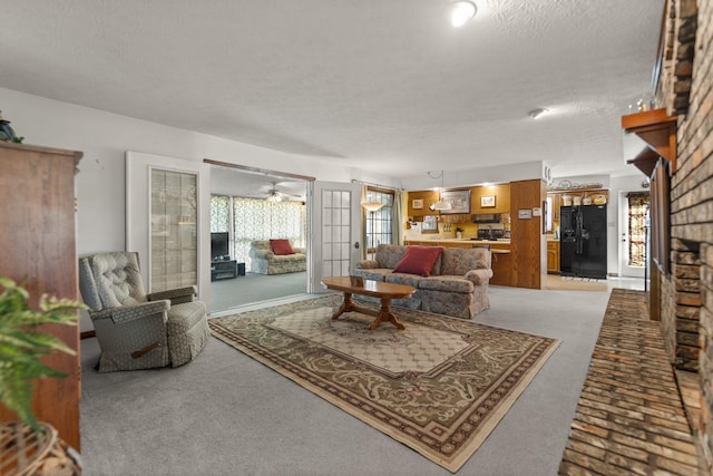 living room featuring ceiling fan, a textured ceiling, and carpet flooring