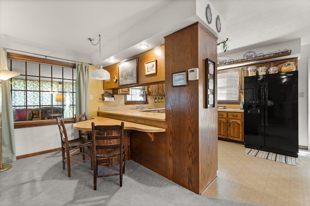 kitchen featuring black fridge, decorative light fixtures, and sink