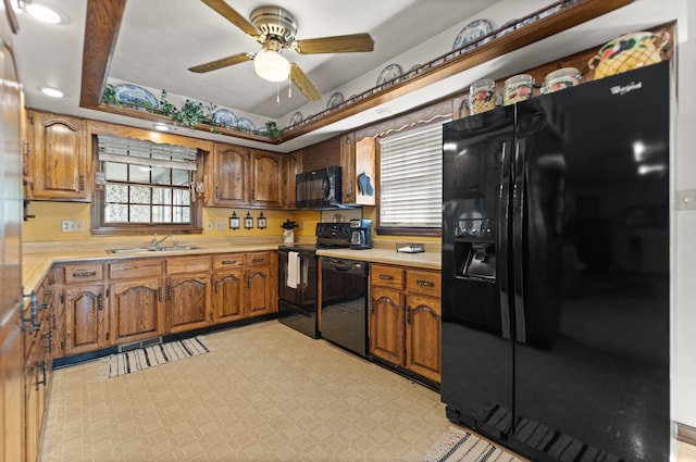 kitchen featuring ceiling fan, a raised ceiling, sink, and black appliances