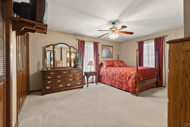 bedroom with light carpet, a closet, ceiling fan, and a textured ceiling