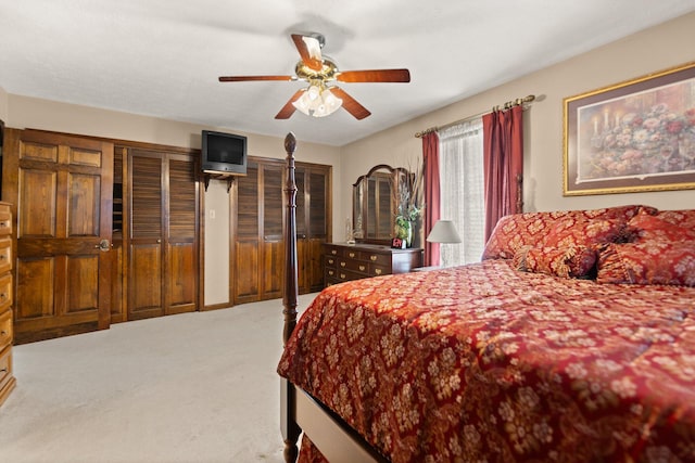 bedroom with two closets, carpet, and ceiling fan