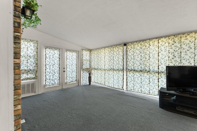 unfurnished living room featuring a textured ceiling, vaulted ceiling, dark carpet, and french doors