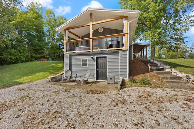 rear view of house with a balcony, a yard, and a patio area