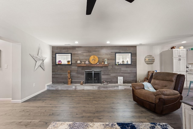 living room with wood-type flooring, ceiling fan, and wooden walls