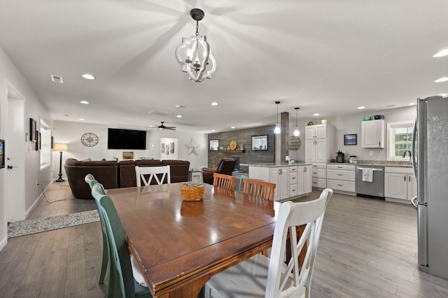 dining area featuring light wood-type flooring and ceiling fan with notable chandelier