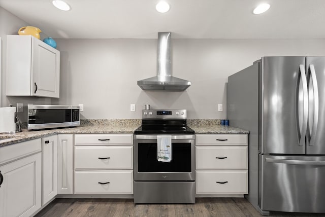 kitchen with light stone counters, dark hardwood / wood-style floors, white cabinetry, wall chimney exhaust hood, and appliances with stainless steel finishes