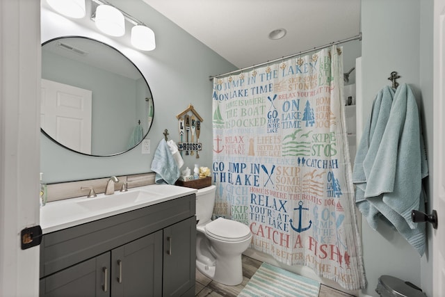 bathroom featuring wood-type flooring, vanity, walk in shower, and toilet