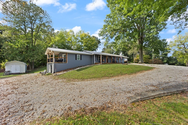 ranch-style house featuring a storage shed and a front lawn