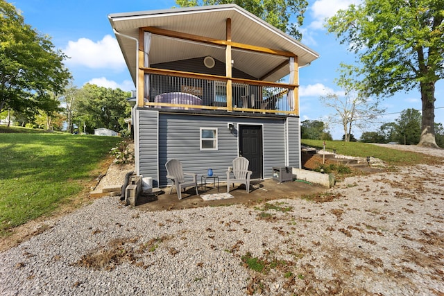 rear view of property featuring a balcony, a yard, and a patio area