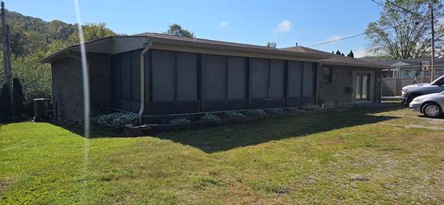 view of home's exterior with a lawn, cooling unit, and a sunroom