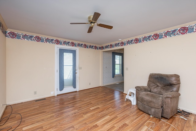 sitting room featuring light hardwood / wood-style flooring, crown molding, and a healthy amount of sunlight