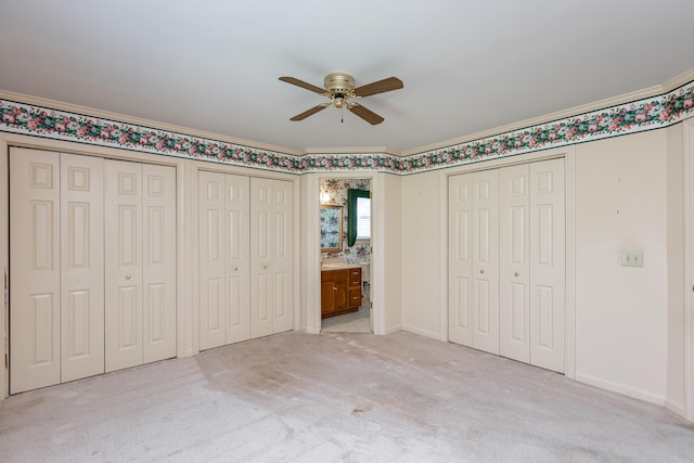 unfurnished bedroom featuring multiple closets, ceiling fan, light colored carpet, and crown molding