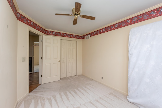 unfurnished bedroom with carpet flooring, ornamental molding, ceiling fan, and a closet