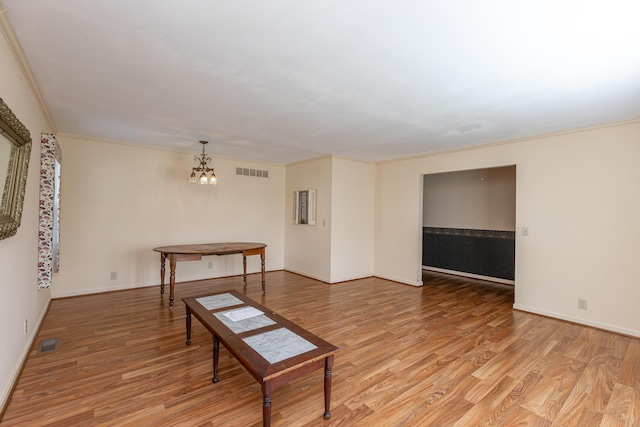 living room with light wood-type flooring, ornamental molding, and an inviting chandelier