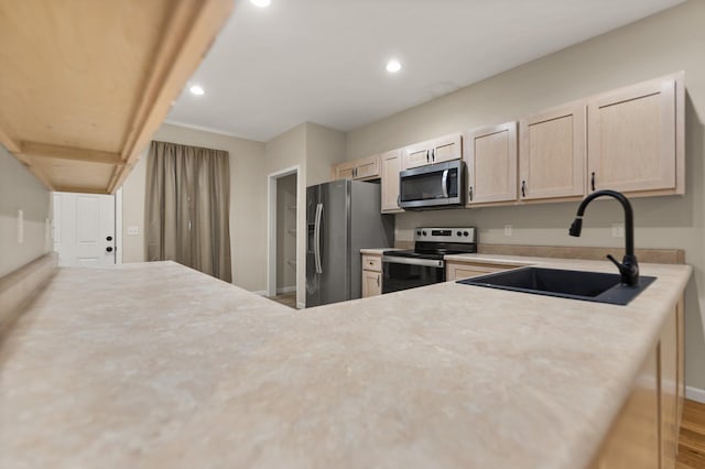 kitchen featuring light brown cabinets, stainless steel appliances, and sink