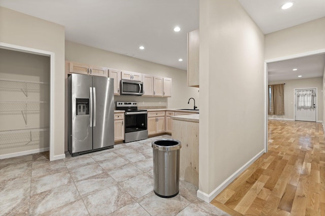 kitchen with appliances with stainless steel finishes, light hardwood / wood-style flooring, light brown cabinetry, and sink