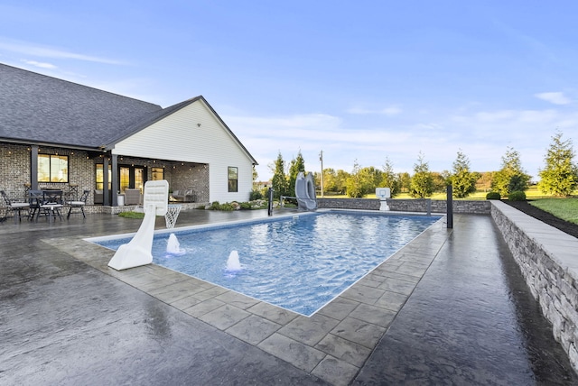 view of swimming pool featuring a water slide, pool water feature, and a patio area