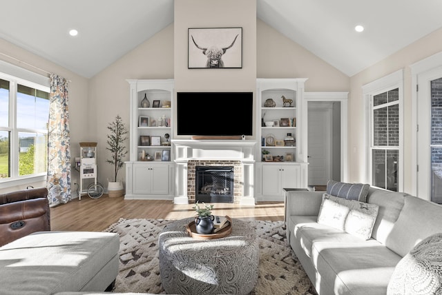 living room with light hardwood / wood-style flooring, a fireplace, and high vaulted ceiling