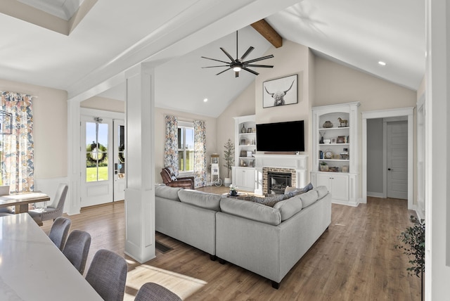 living room featuring ceiling fan, hardwood / wood-style flooring, beamed ceiling, and a fireplace