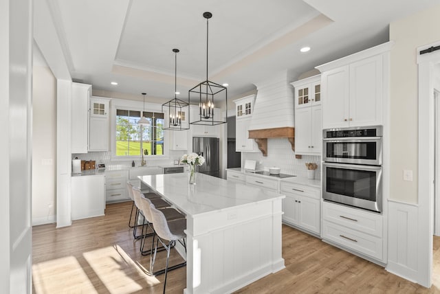 kitchen featuring appliances with stainless steel finishes, a tray ceiling, a kitchen island, and white cabinets