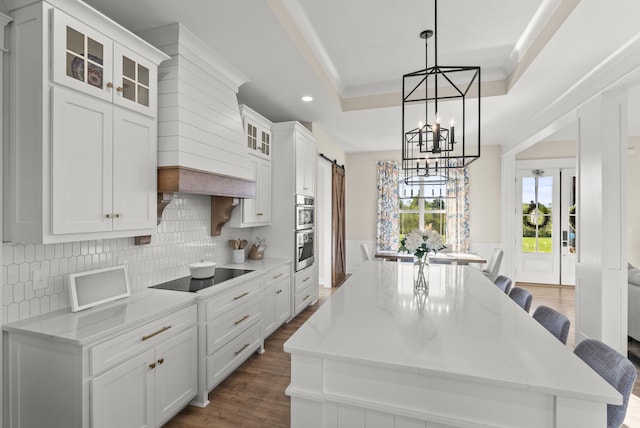 kitchen featuring a kitchen island, a barn door, dark hardwood / wood-style floors, and white cabinets