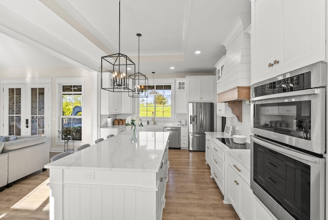 kitchen with a healthy amount of sunlight, stainless steel appliances, a kitchen island, and white cabinets