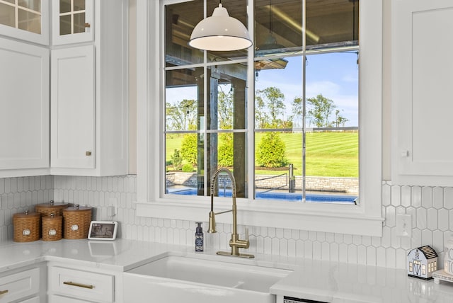 interior space with white cabinetry, sink, and backsplash